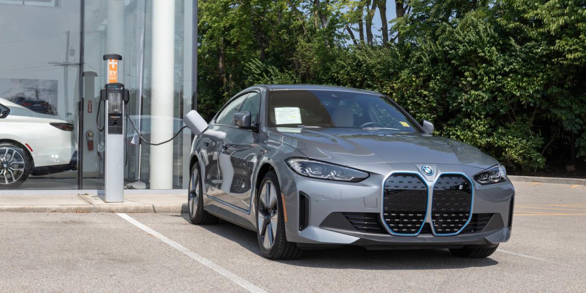 A silver BMW i4 price is parked at a dealership to charge the electric battery.
