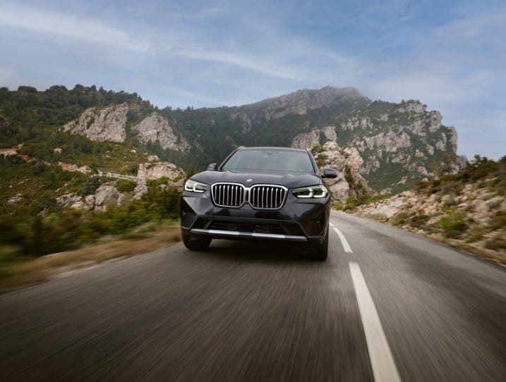 One of the most reliable bmw models driving down a highway with a mountain landscape background.
