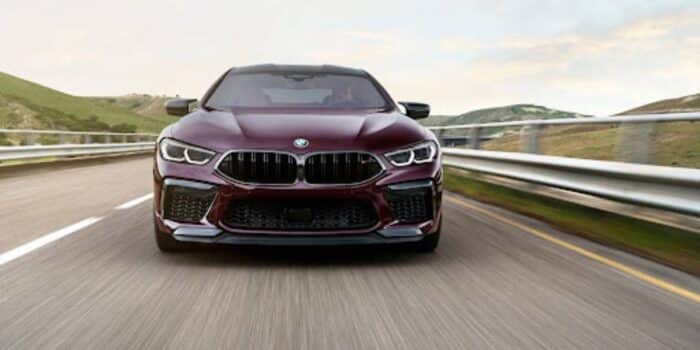 A BMW sedan driving down the highway with BMW warranty.