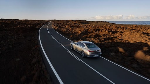 A BMW driving down an empty highway at sunrise.