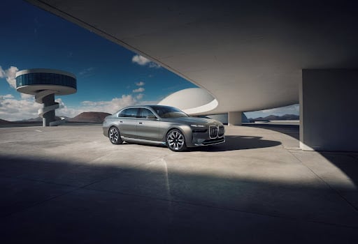 A BMW parked under a bridge on the highway.