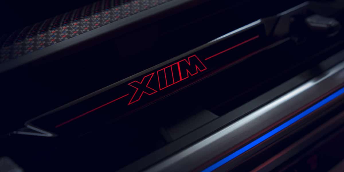 Illuminated BMW M Series door sill plate featuring red XMM logo, highlighting the high-performance and luxury design elements of BMW’s M lineup.