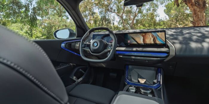 Interior view of 2025 BMW X3 showing steering wheel, curved digital display, and dashboard design with premium materials.