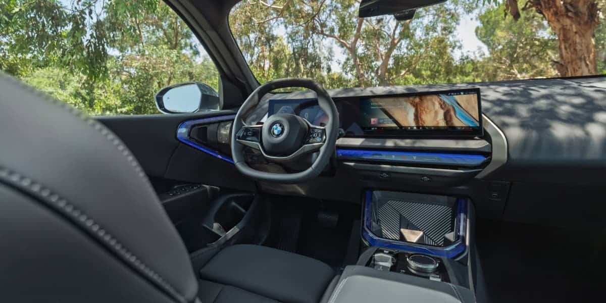 Interior view of 2025 BMW X3 showing steering wheel, curved digital display, and dashboard design with premium materials.