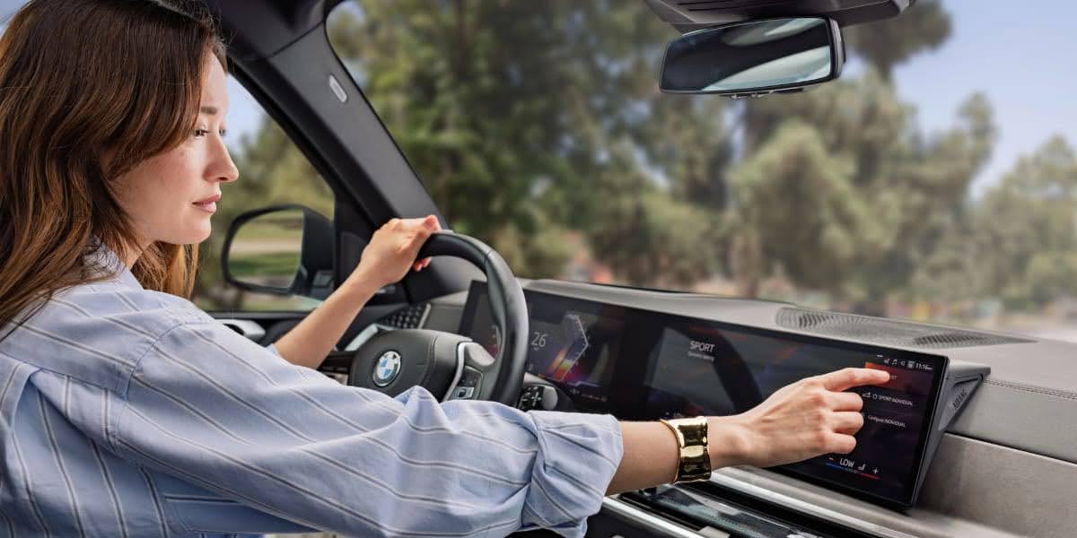 Driver using BMW infotainment screen showing BMW driver assistance features inside a modern BMW interior.