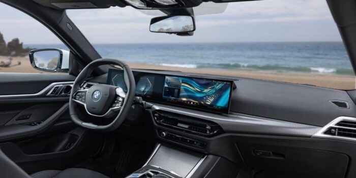 Interior view of BMW i4 parked by the beach showing dashboard and displays, illustrating luxury electric design and BMW i4 range focus.