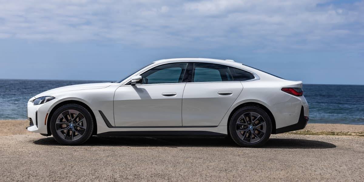 Side profile of the 2026 BMW i4 electric sedan parked near the ocean, highlighting its sleek design and sporty proportions